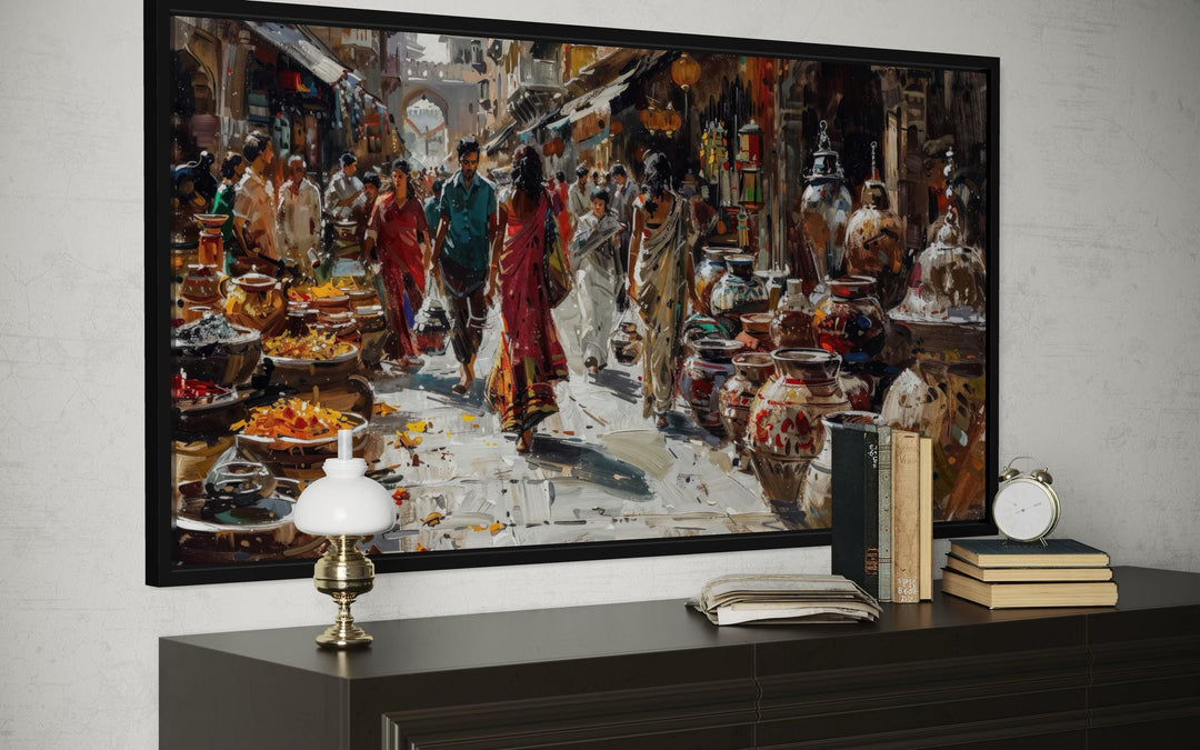 Framed Indian market canvas painting showing a vibrant bazaar scene above a dark wood console table.