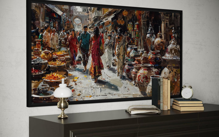 Framed Indian market canvas painting showing a vibrant bazaar scene above a dark wood console table.