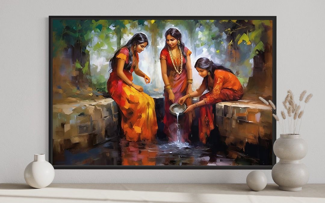 Framed canvas art of three Indian women in vibrant saris gathering water at a well.