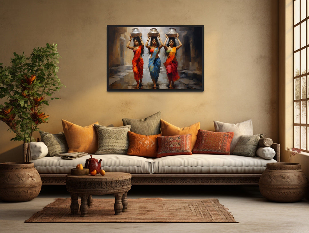 Framed canvas wall art of three Indian women in vibrant saris carrying water pots on their heads.