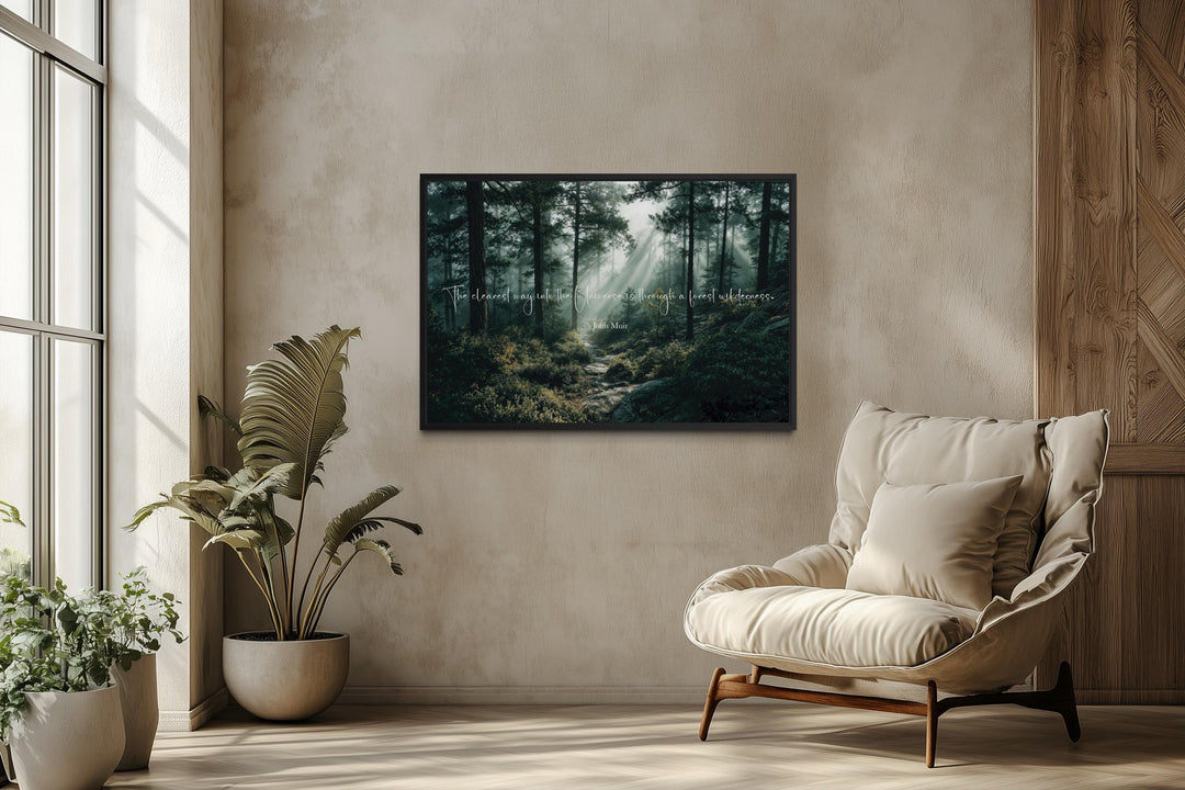 A framed forest landscape canvas with a John Muir quote hangs in a minimalist, sunlit room.
