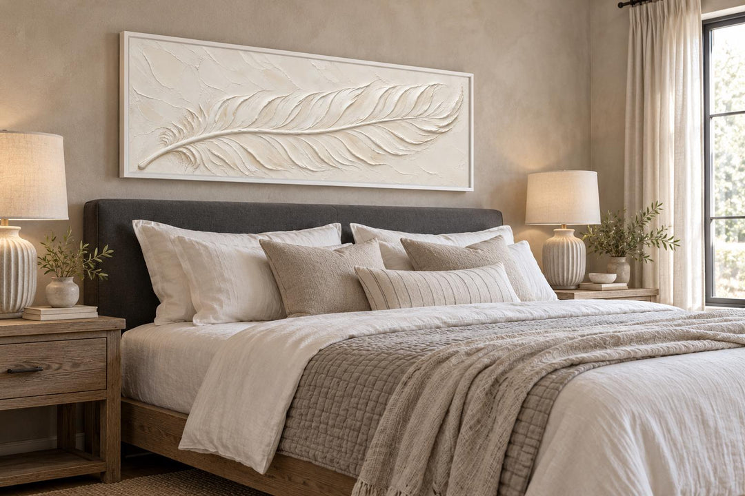 Long narrow canvas wall art featuring a sculpted ivory feather with a plaster effect over a bed.