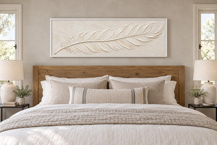 Ivory feather plaster-effect long canvas wall art centered above a wooden bed with neutral bedding.