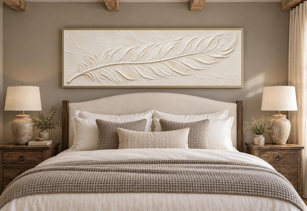 Long narrow canvas wall art of a cream plaster-effect feather above a bed in a neutral bedroom.