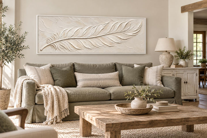 Long narrow canvas wall art featuring a cream plaster-effect feather above a green sofa.