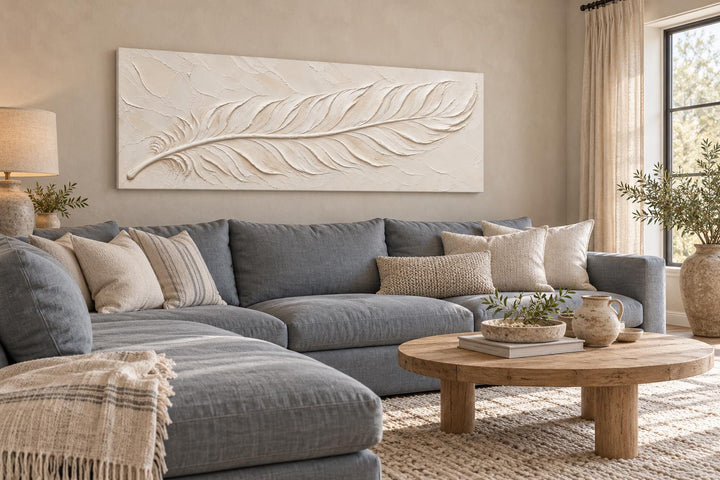 Ivory Feather long narrow canvas wall art with a cream plaster effect above a blue sectional sofa.