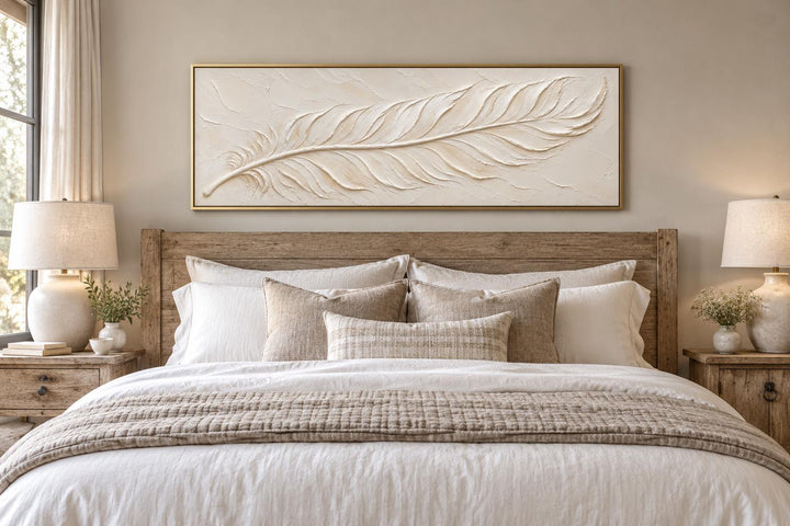 Ivory feather plaster effect canvas wall art in a gold frame above a wooden bed in a neutral room.