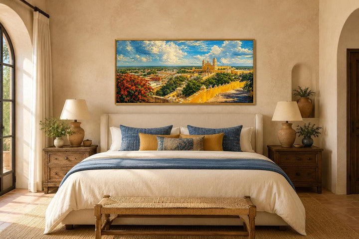 Izamal Cityscape canvas wall art with yellow colonial buildings above a bed in a warm bedroom.
