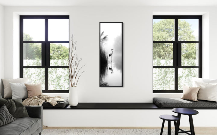 Vertical narrow canvas print of a Japanese crane in black and white zen style on a white wall.
