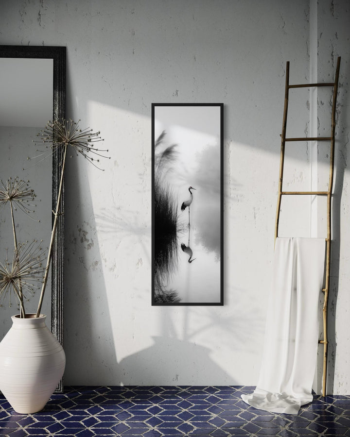 Vertical narrow black and white canvas print of a Japanese crane reflected in a serene lake.