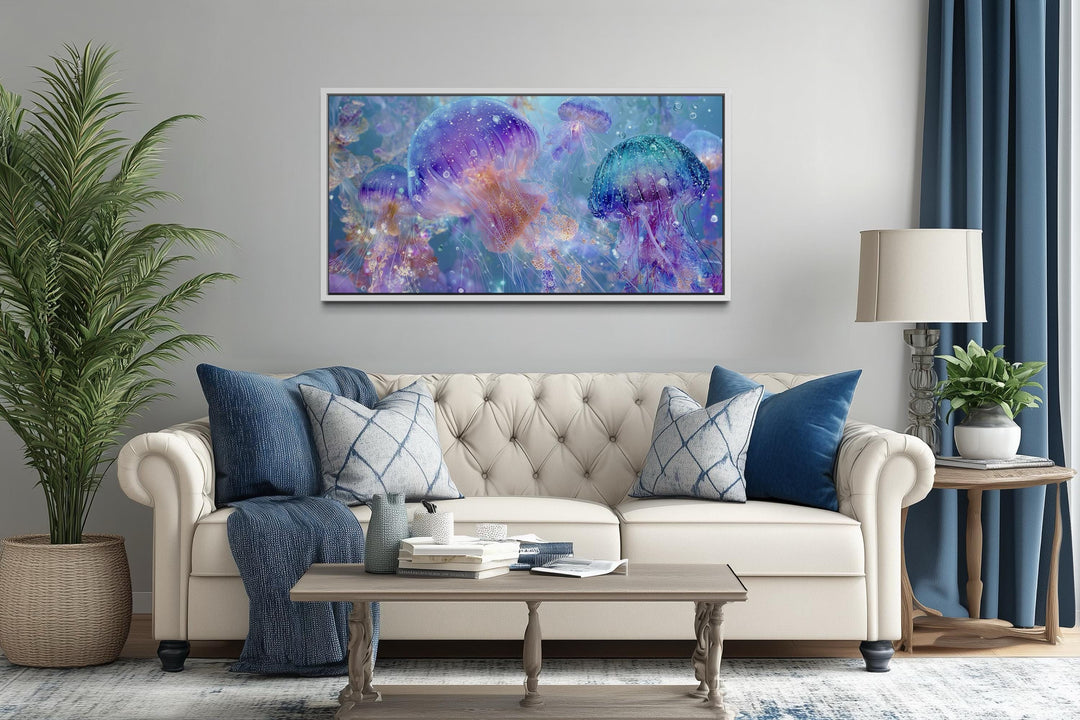 A horizontal canvas print of colorful purple and blue jellyfish hangs above a neutral tufted sofa.