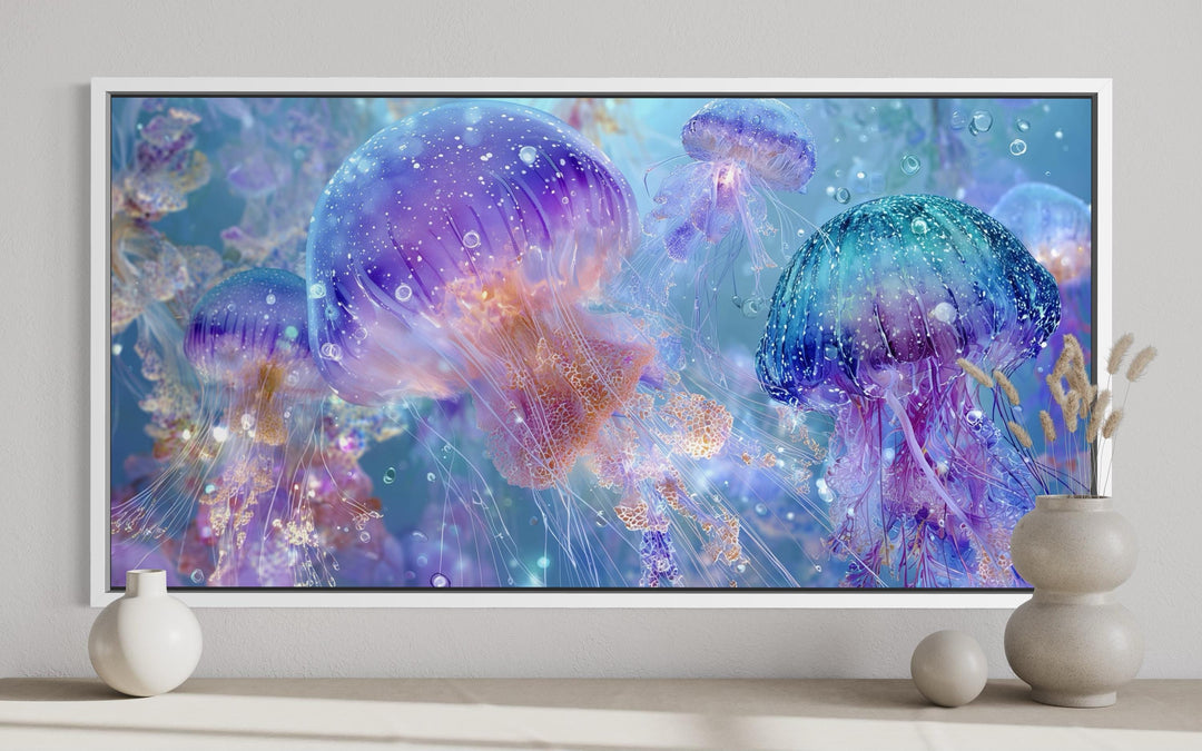Colorful jellyfish canvas wall art in purple, blue, and aqua tones displayed in a white frame.