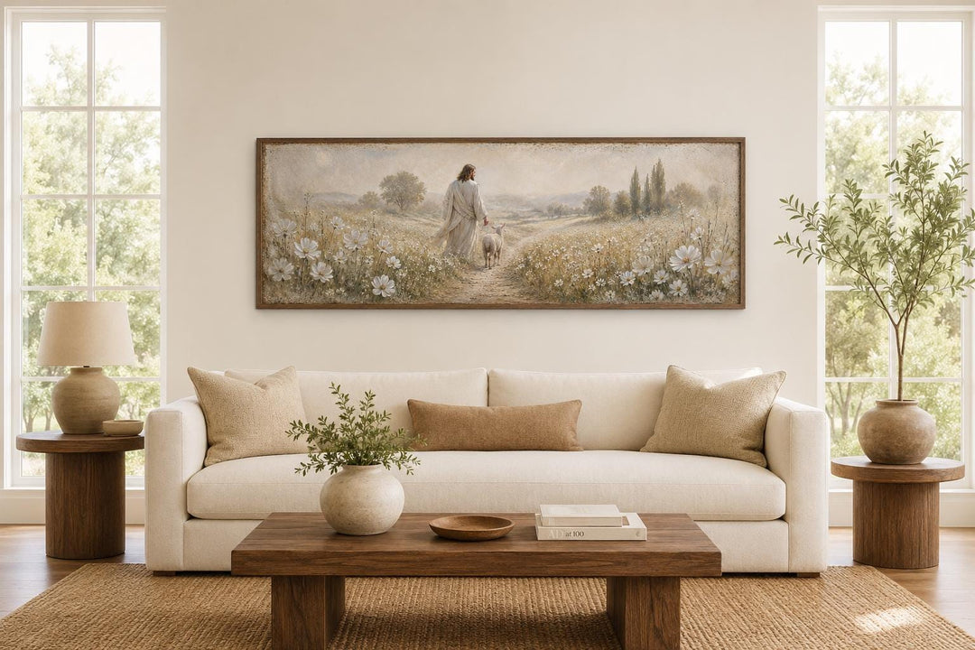 Jesus and lamb in a wildflower field wall art canvas print above a sofa in a neutral living room.