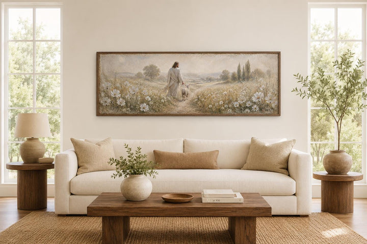 Jesus and lamb in a wildflower field wall art canvas print above a sofa in a neutral living room.