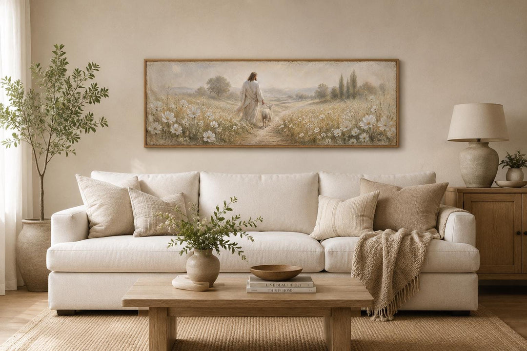Jesus and lamb in a wildflower field canvas print hanging above a white sofa in a neutral room.