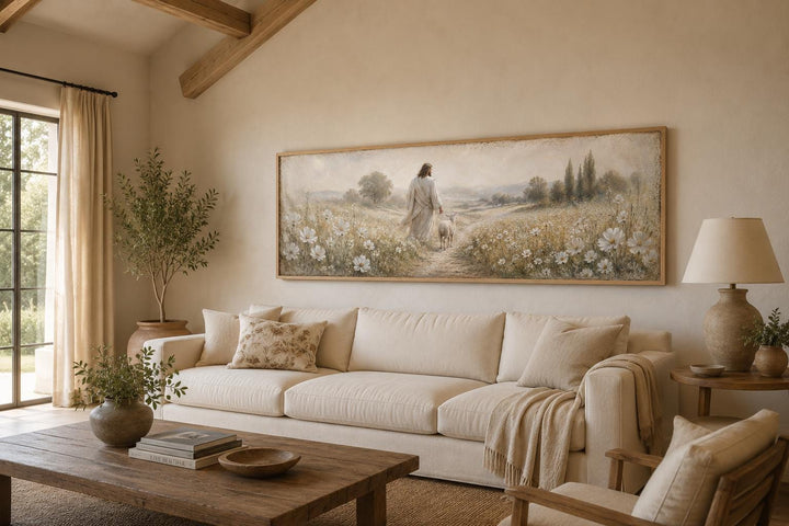 Jesus and lamb in a wildflower field canvas print hanging above a neutral sofa in a living room.