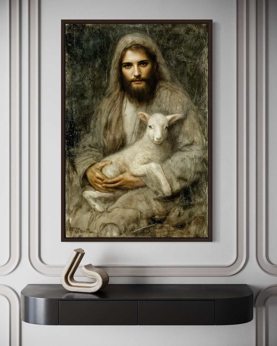 Framed canvas wall art of Jesus holding a lamb, displayed above a modern black console table.