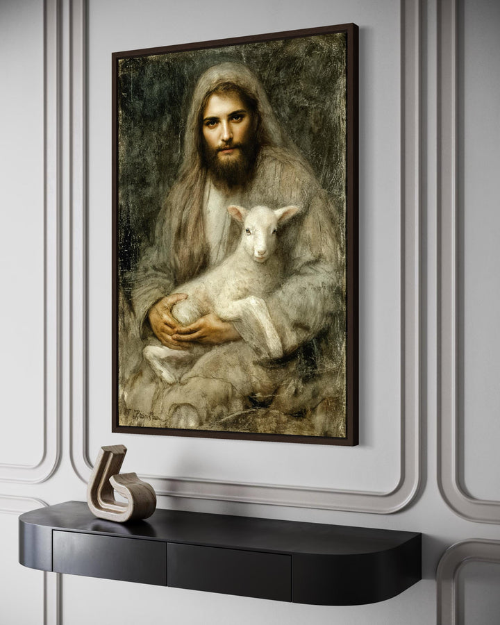 A framed canvas painting of Jesus holding a lamb, displayed on a wall above a black console table.