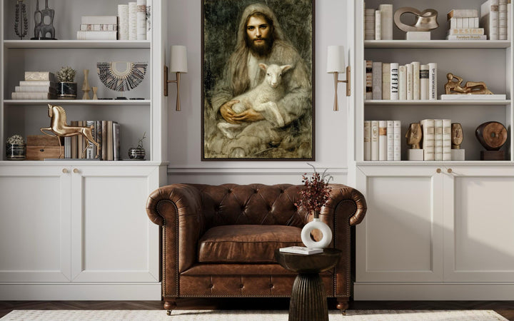 Framed canvas wall art of Jesus holding a lamb, displayed above a brown leather armchair.
