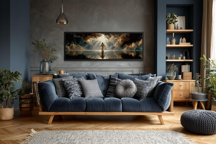Panoramic canvas print of Jesus walking on water displayed above a blue sofa in a modern living room.