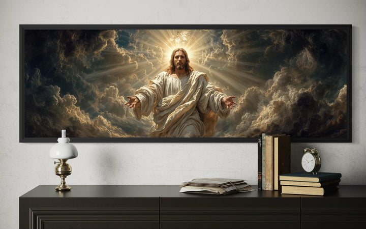 Panoramic canvas print of Jesus with open arms amidst radiant clouds, framed above a dark console.
