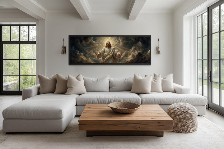 Panoramic canvas print of Jesus with open arms in a dramatic sky, hung above a modern sectional sofa.