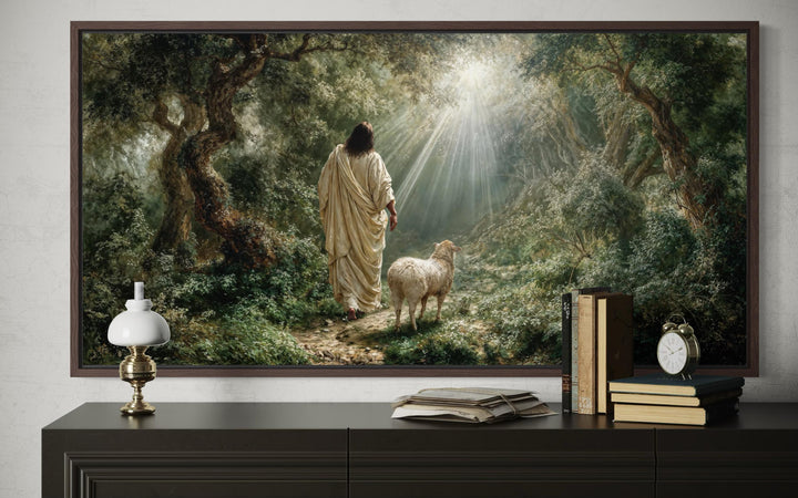 Jesus the Good Shepherd and lamb in a forest canvas wall art displayed above a dark wood console.