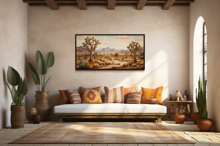 Framed Joshua tree desert landscape painting on a wall above a white sofa with colorful pillows.