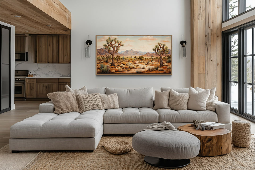 Framed Joshua tree desert landscape painting on a white wall above a modern sectional sofa.