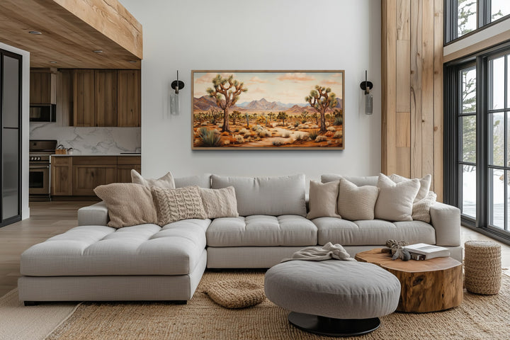 Framed Joshua tree desert landscape painting on a white wall above a modern sectional sofa.