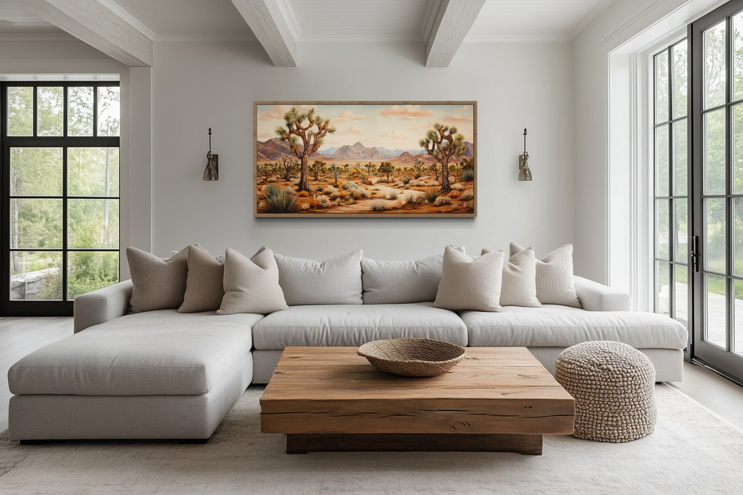 Framed Joshua tree desert landscape canvas painting hanging above a neutral sectional sofa.