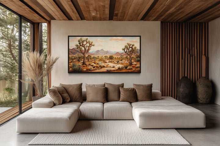 Framed Joshua tree desert landscape painting on a wall above a modern sectional sofa.