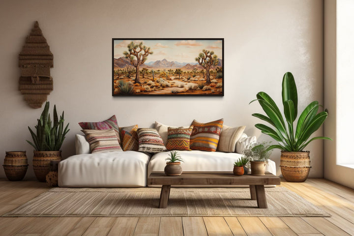 Framed Arizona canvas painting of Joshua trees in a desert landscape above a white sofa.