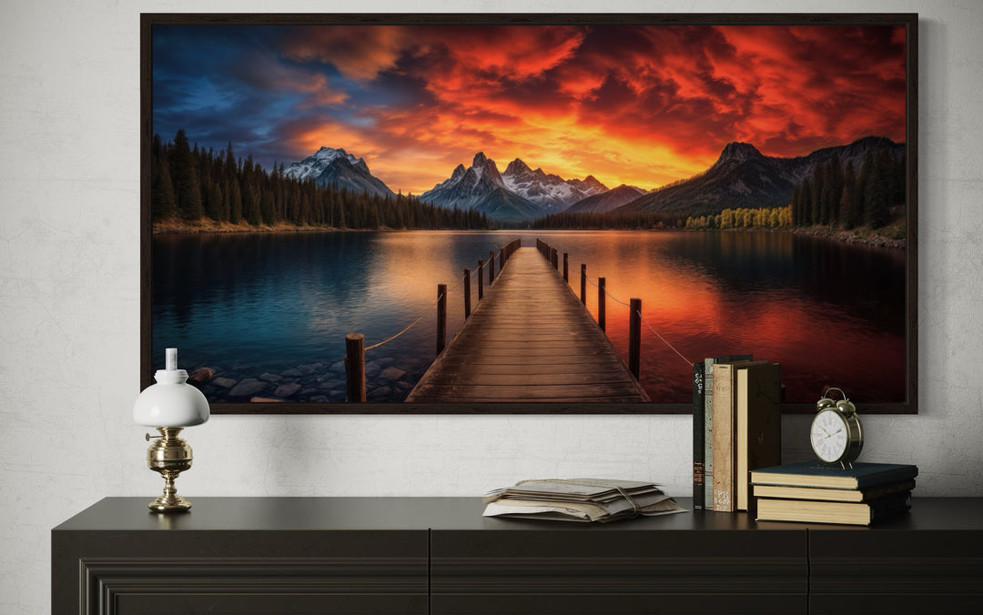Framed canvas wall art of a wooden pier on a lake with a vibrant sunset and mountain backdrop.
