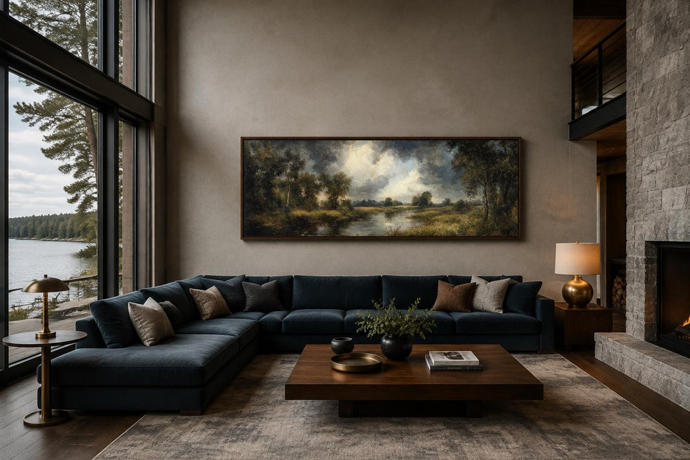 Vintage oil-painted lake forest landscape canvas wall art in a dark wood frame above a blue sofa.