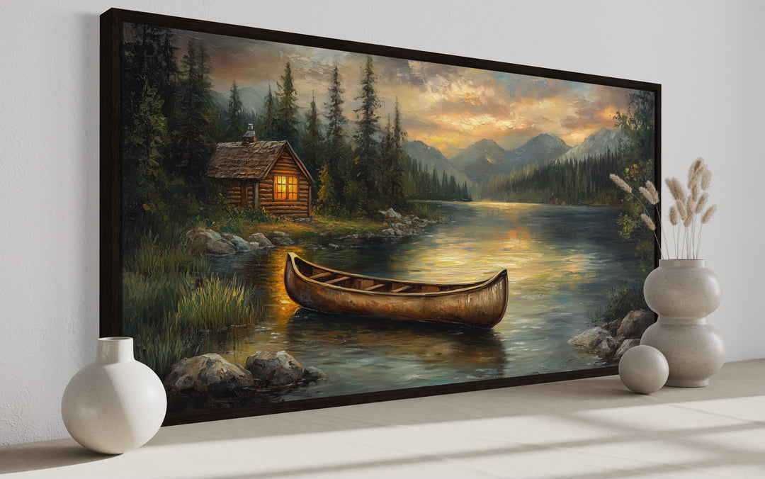Lake house and rustic wooden canoe canvas wall art in a dark frame on a white wall.