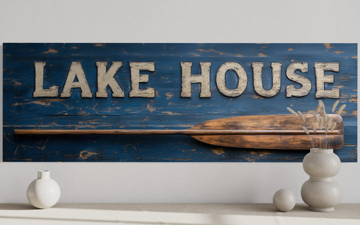Rustic Lake House sign on distressed blue wood with a wooden oar and white 3D lettering.