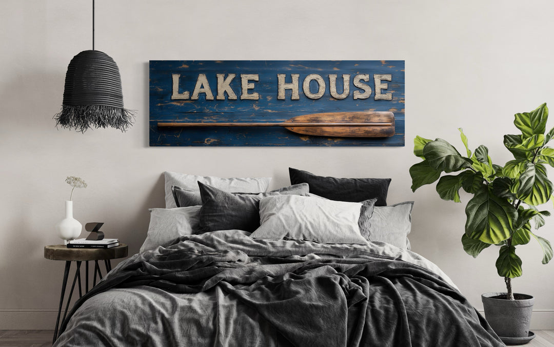 Lake House Sign With Oar long horizontal framed canvas wall art above a bed in a rustic bedroom.