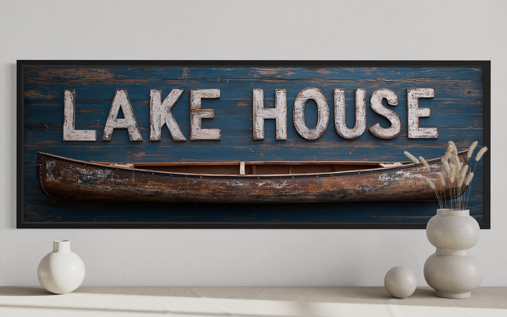Framed horizontal canvas art of a rustic blue wooden sign with 'LAKE HOUSE' and a wooden canoe.