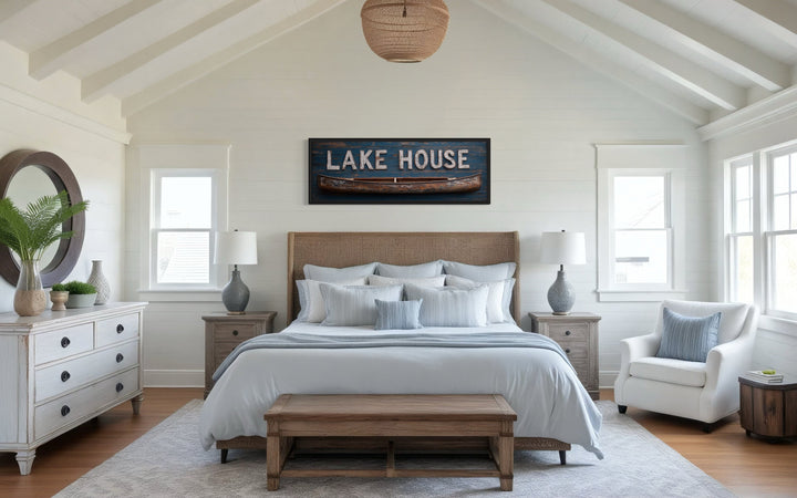 Lake House sign with wooden canoe framed canvas wall art hanging above a bed in a rustic bedroom.