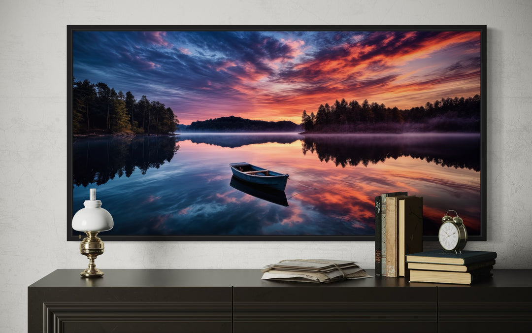 Framed canvas print of a boat on a calm lake at sunset, displayed above a dark wooden console table.