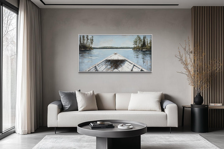 Lake View wall art featuring a white canoe on a blue lake, hung above a modern sofa in a living room.