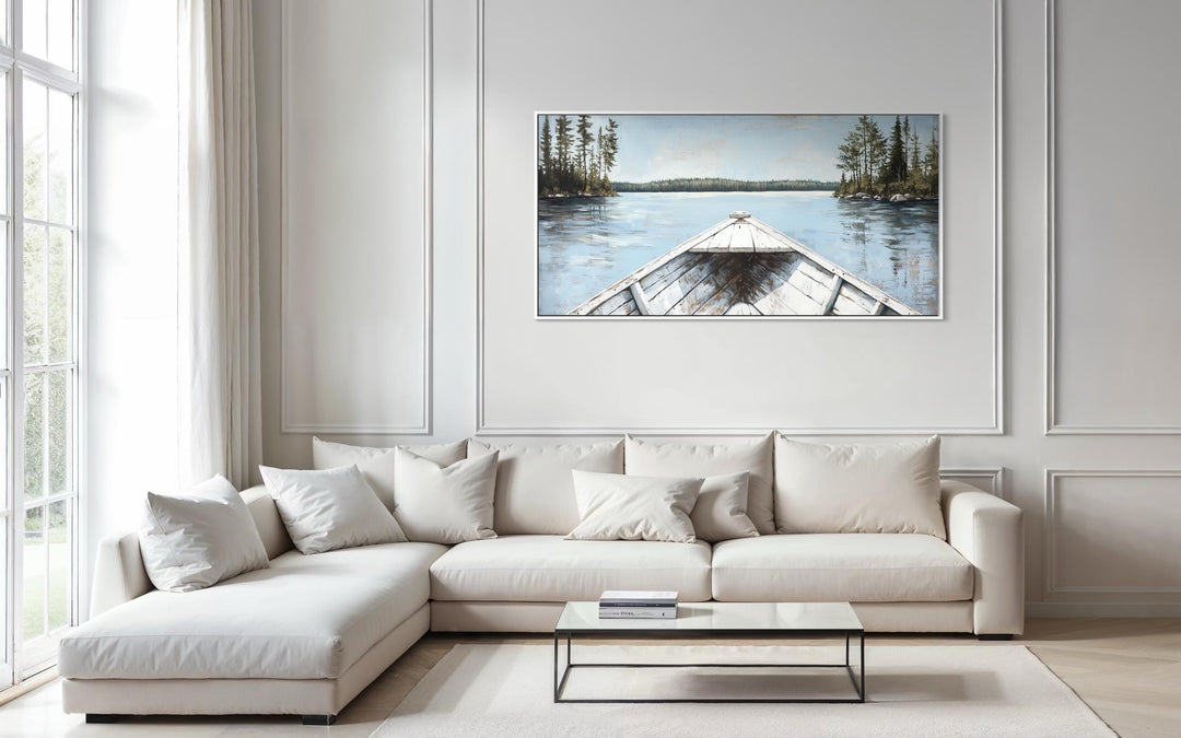 Lake View wall art featuring a white canoe on a blue landscape canvas above a modern white sofa.