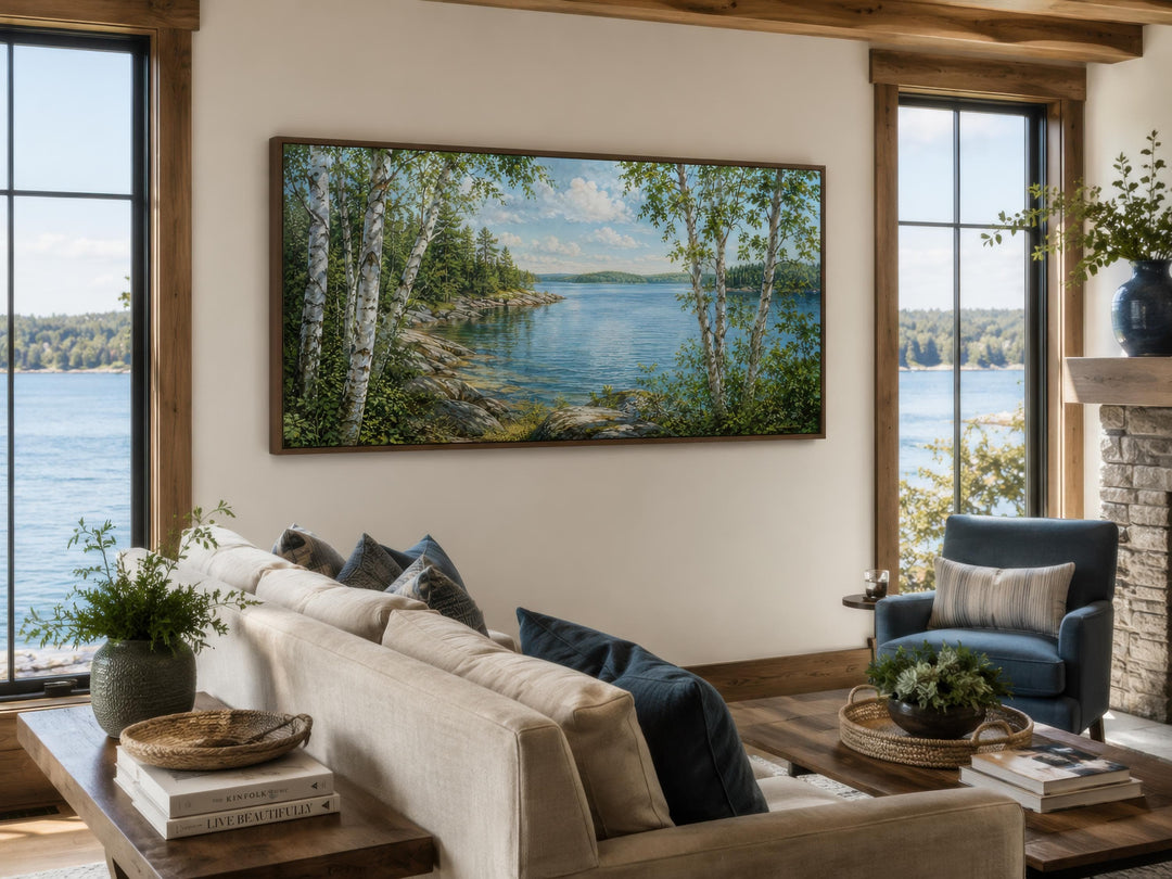 Wide horizontal birch tree canvas print of a serene lake scene above a sofa in a lake house room.