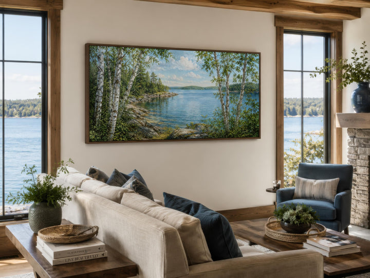 Wide horizontal birch tree canvas print of a serene lake scene above a sofa in a lake house room.