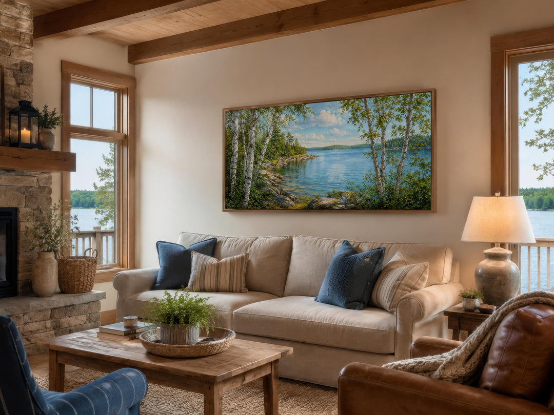 Wide horizontal birch tree canvas print hanging above a sofa in a cozy lake house living room.