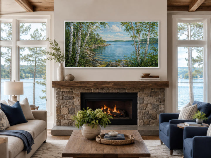 Birch tree canvas print of a summer lake scene mounted above a stone fireplace in a living room.