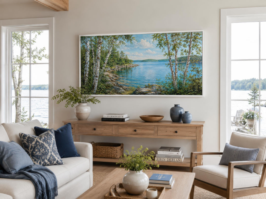 Large horizontal canvas print of a birch tree lake scene above a console table in a living room.