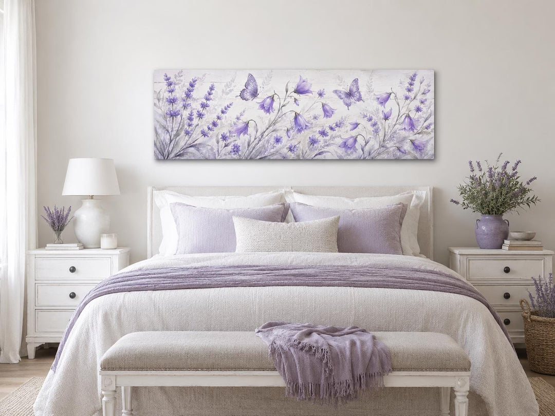 Long horizontal canvas art of lavender wildflowers and butterflies above a bed with purple linens.