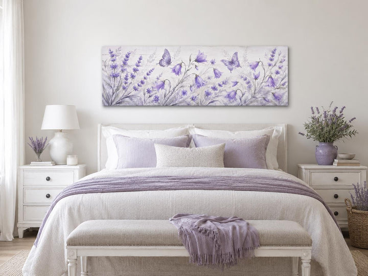 Long horizontal canvas art of lavender wildflowers and butterflies above a bed with purple linens.